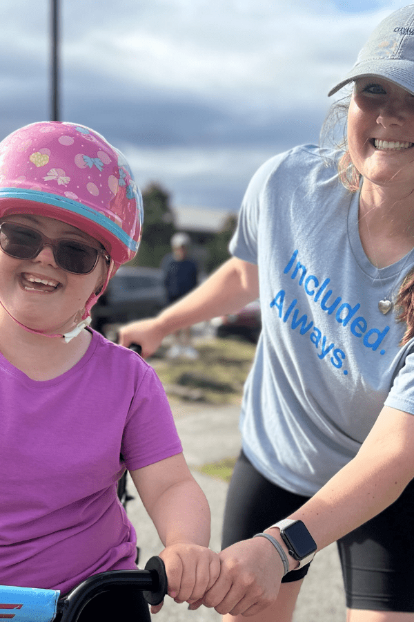 Participant riding a bike being guided by a volunteer